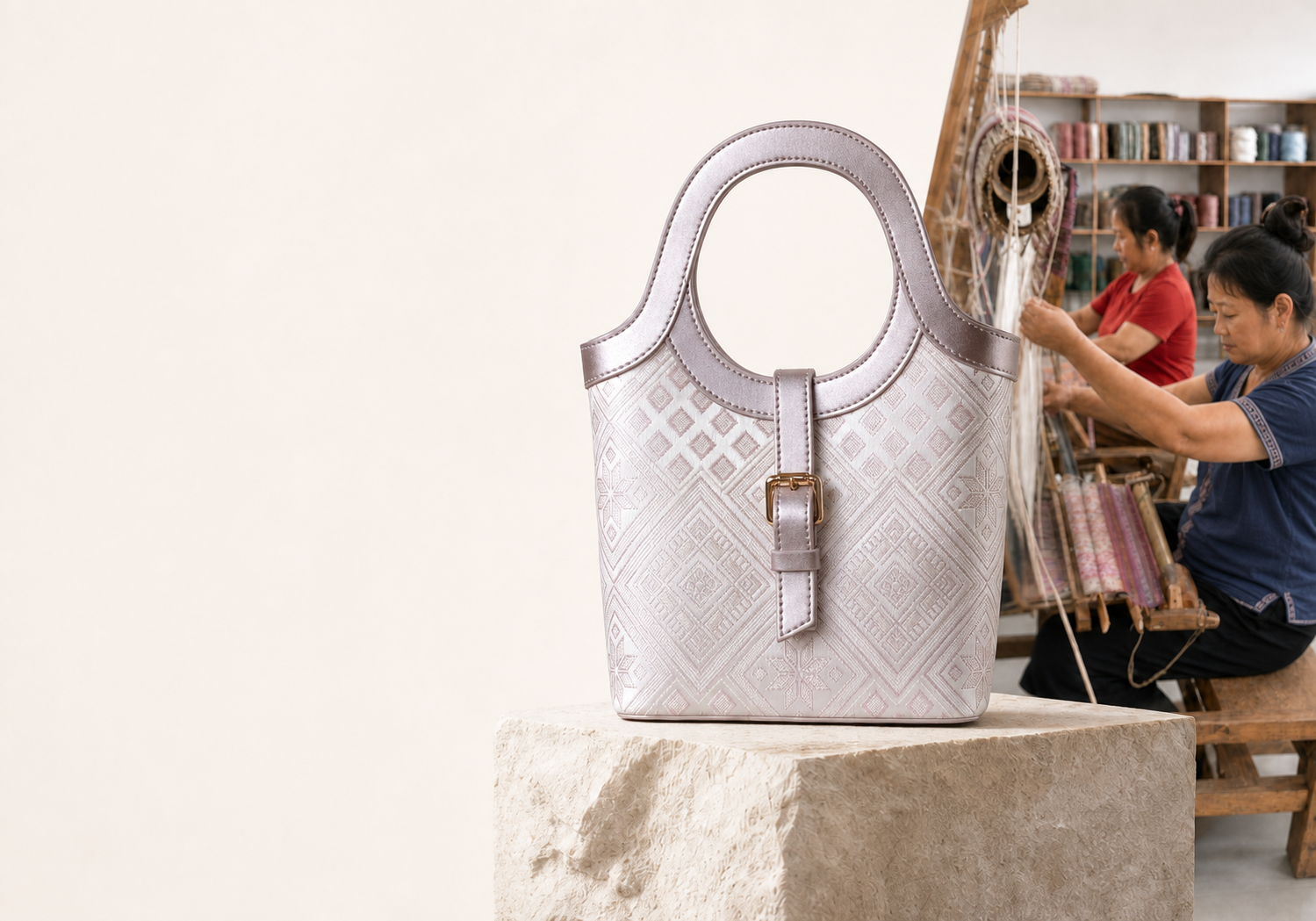 Ivory Zhuang-brocade bags displayed beside an artisan weaving in the atelier